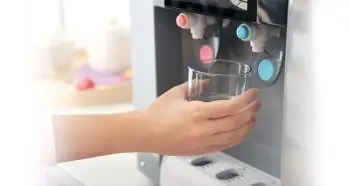 Hand of a lady holding a glass bottle and filling it with water from a water purifier